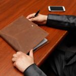 The Art of Drawing Readers In: Your attractive post title goes here Male executive writing notes during a business meeting using a leather notebook.